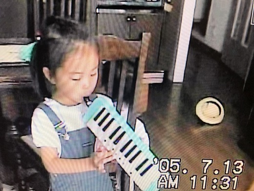 5歳のとき、鍵盤にカラフルなシールを貼って鍵盤ハーモニカを練習する著者