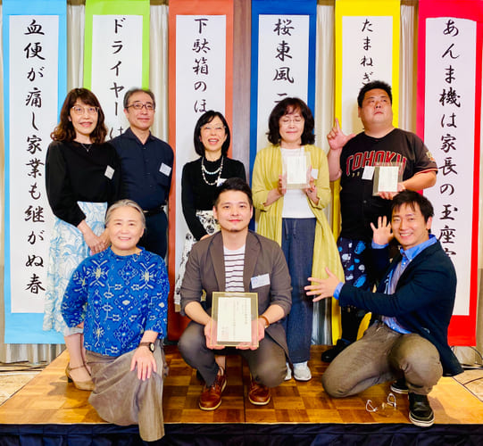 大賞を受賞したツナ好さん（写真 前列中央）と、選者・夏井いつきさん（同左）、司会の家藤正人さん（同右）